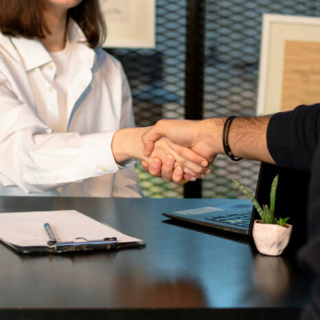 A man and a woman shaking hands at a desk